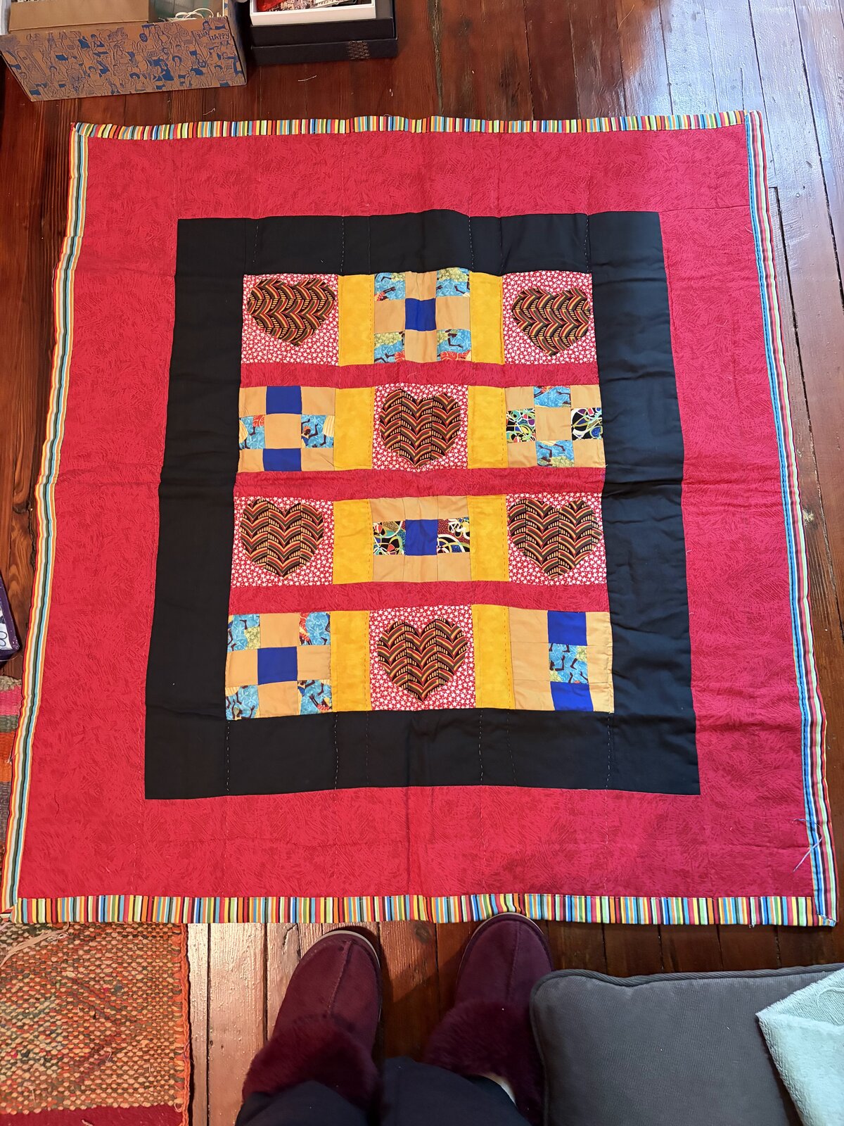 Hand-pieced quilt with bold red and black borders and a center grid of African-print heart blocks