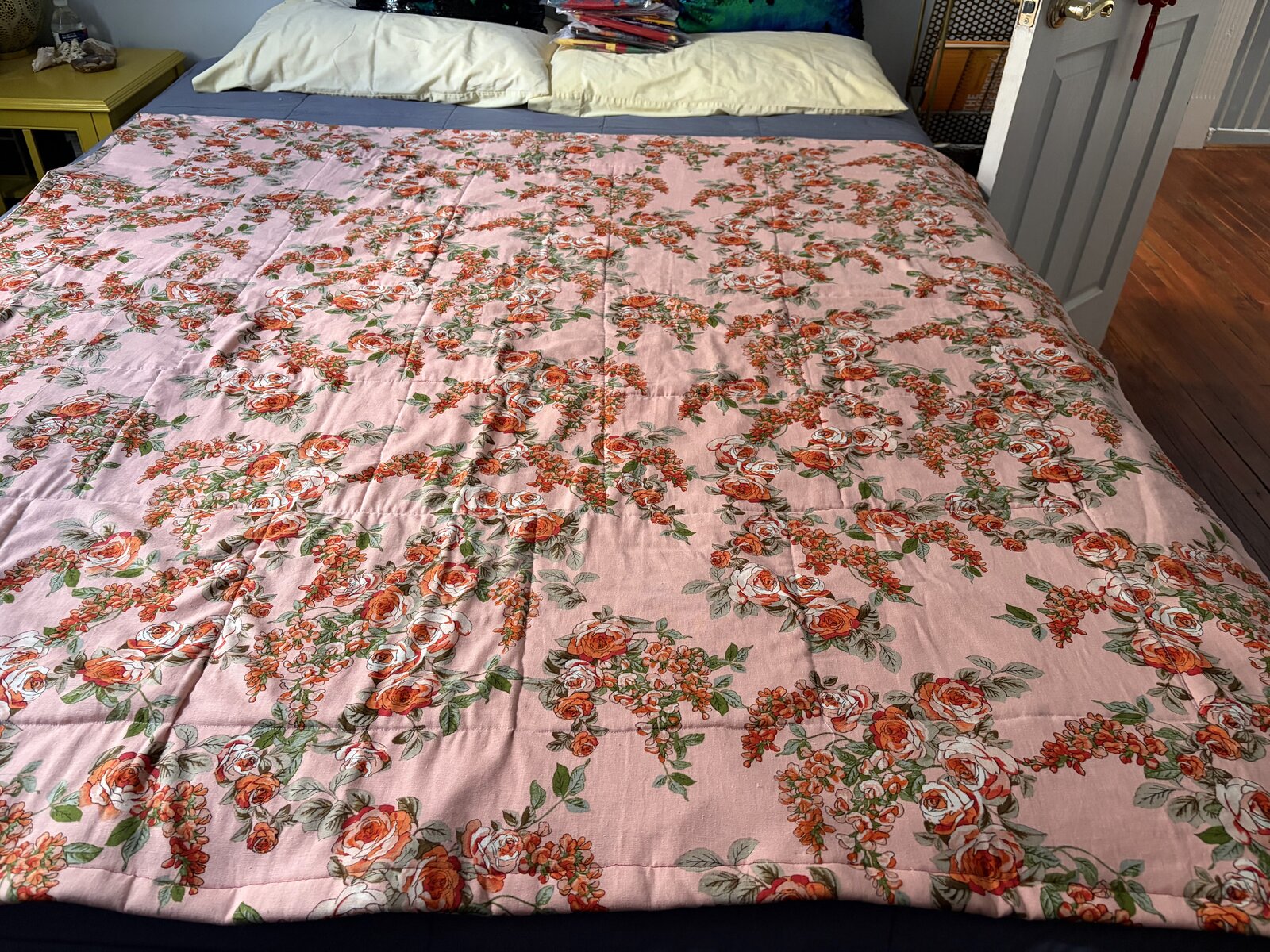 Pink rose-print quilt spread across a bed, soft and floral all over