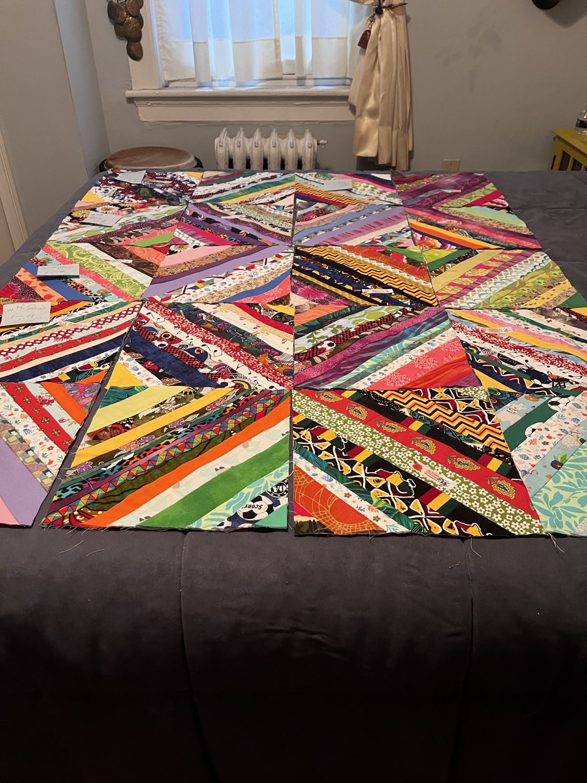 Kaleidoscopic quilt blocks made of narrow strips of scrap fabric in dozens of colors and prints